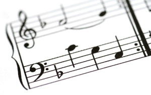 a close up image of a sheet of printed music with the focus on the base clef on a music staf